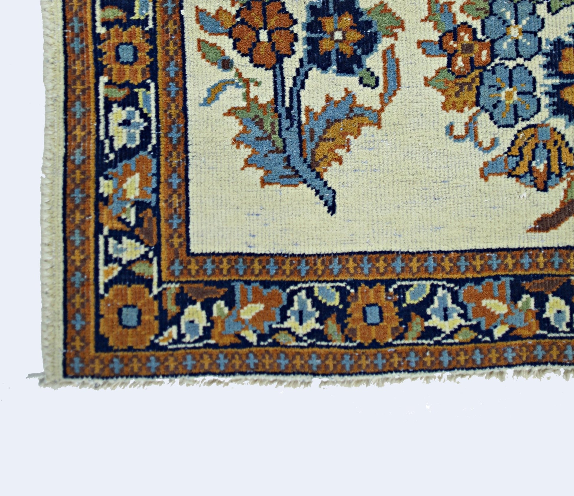 A vintage Persian Sarouk rug featuring a floral pattern in blue and orange on a cream background.