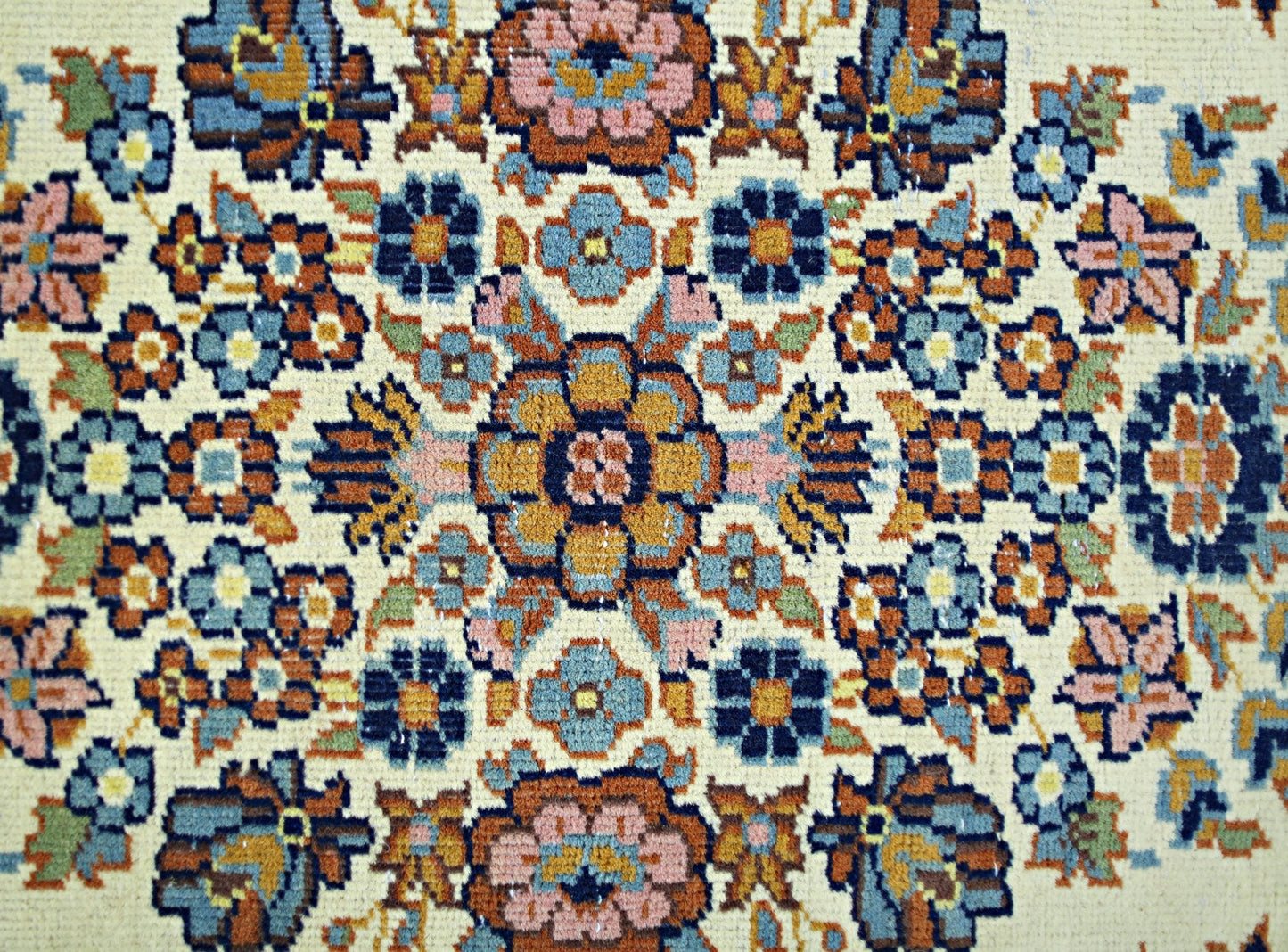 A vintage Persian Sarouk rug featuring a detailed floral medallion pattern in blue and orange.