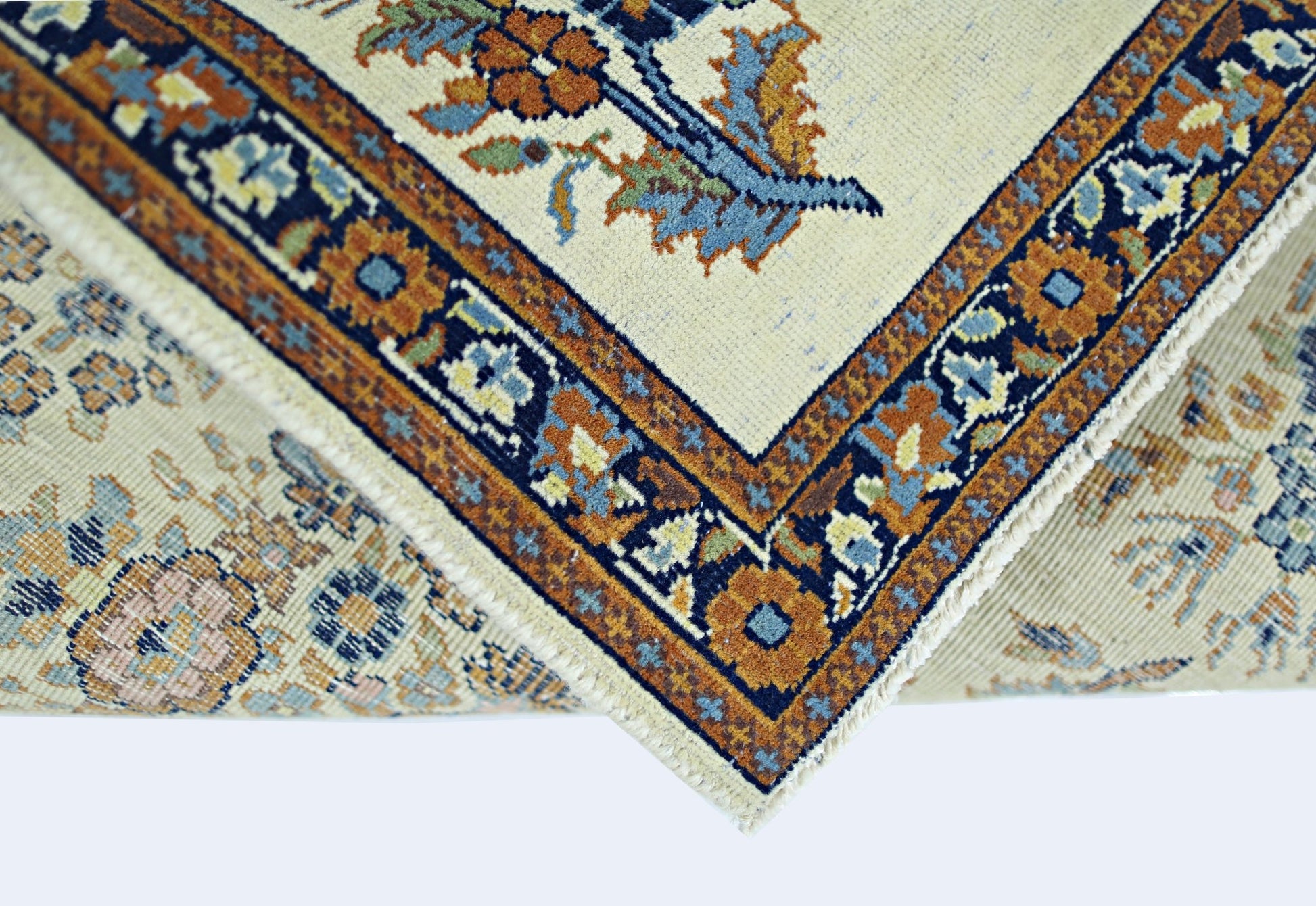 A folded vintage Persian Sarouk rug featuring a floral pattern in blue, orange, and cream tones.