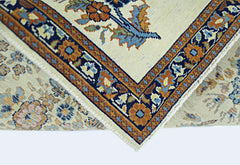 A folded vintage Persian Sarouk rug featuring a floral pattern in blue, orange, and cream tones.