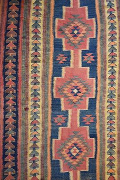 Handmade Persian tribal kilim rug featuring geometric patterns in blue, pink, and yellow.