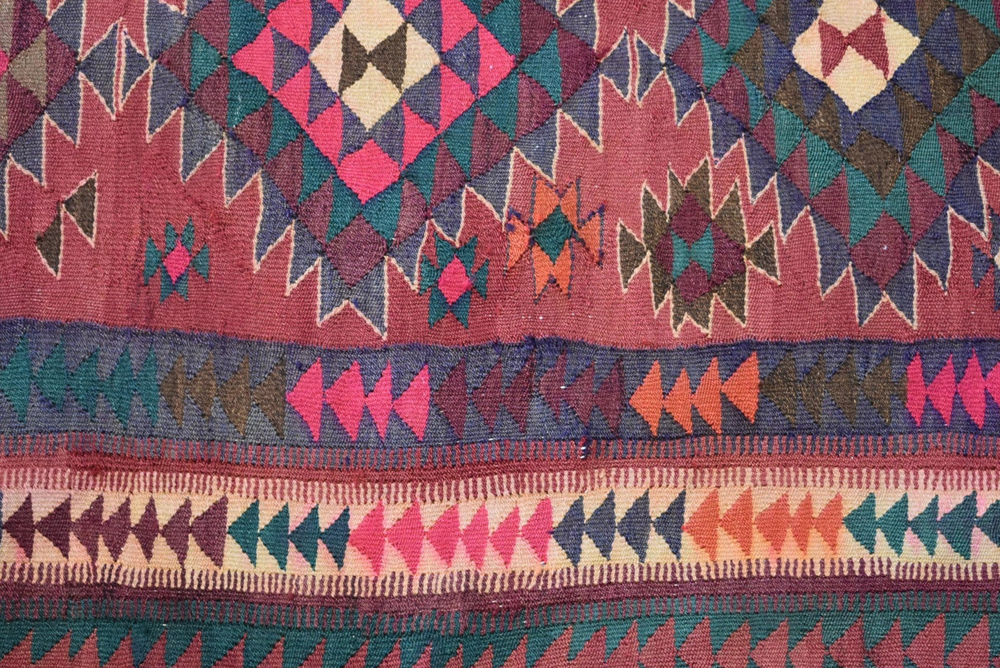 A handmade Persian tribal kilim rug featuring geometric patterns in red, blue, and orange wool.