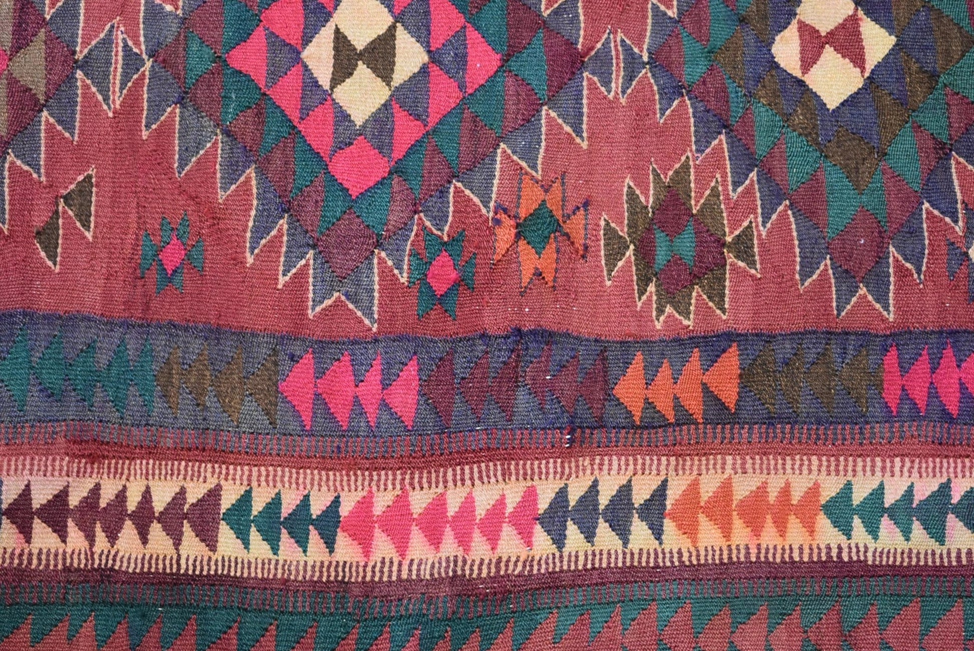 A handmade Persian tribal kilim rug featuring geometric patterns in red, blue, and orange wool.