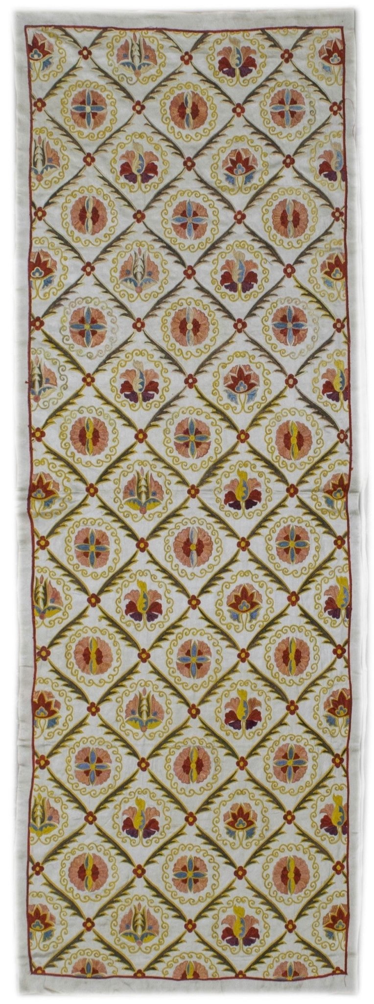 A handmade silk Uzbek suzani featuring a repeating floral pattern in a diamond grid.