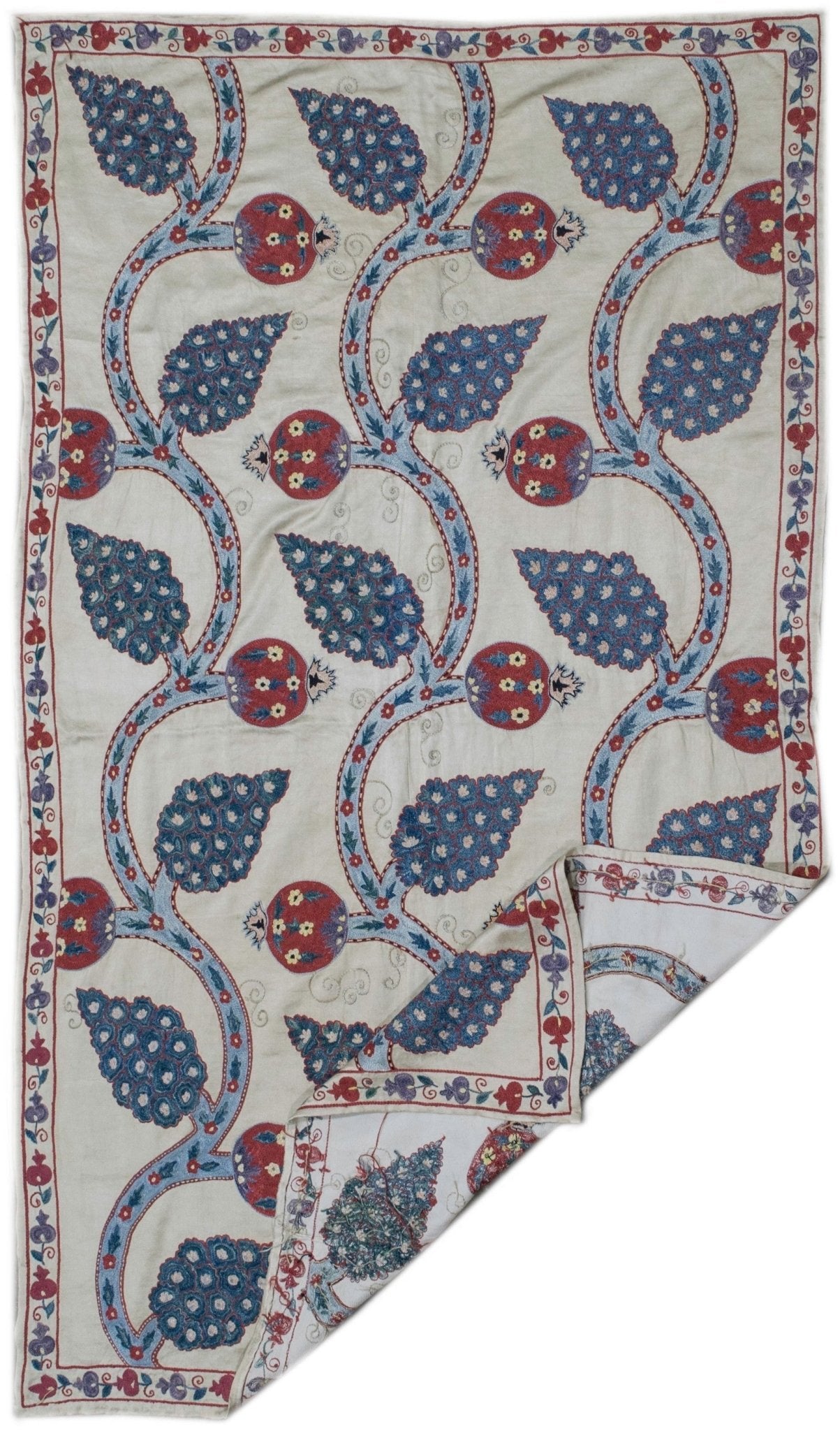 Handmade silk Uzbek suzani featuring intricate blue and red floral and pomegranate embroidery.