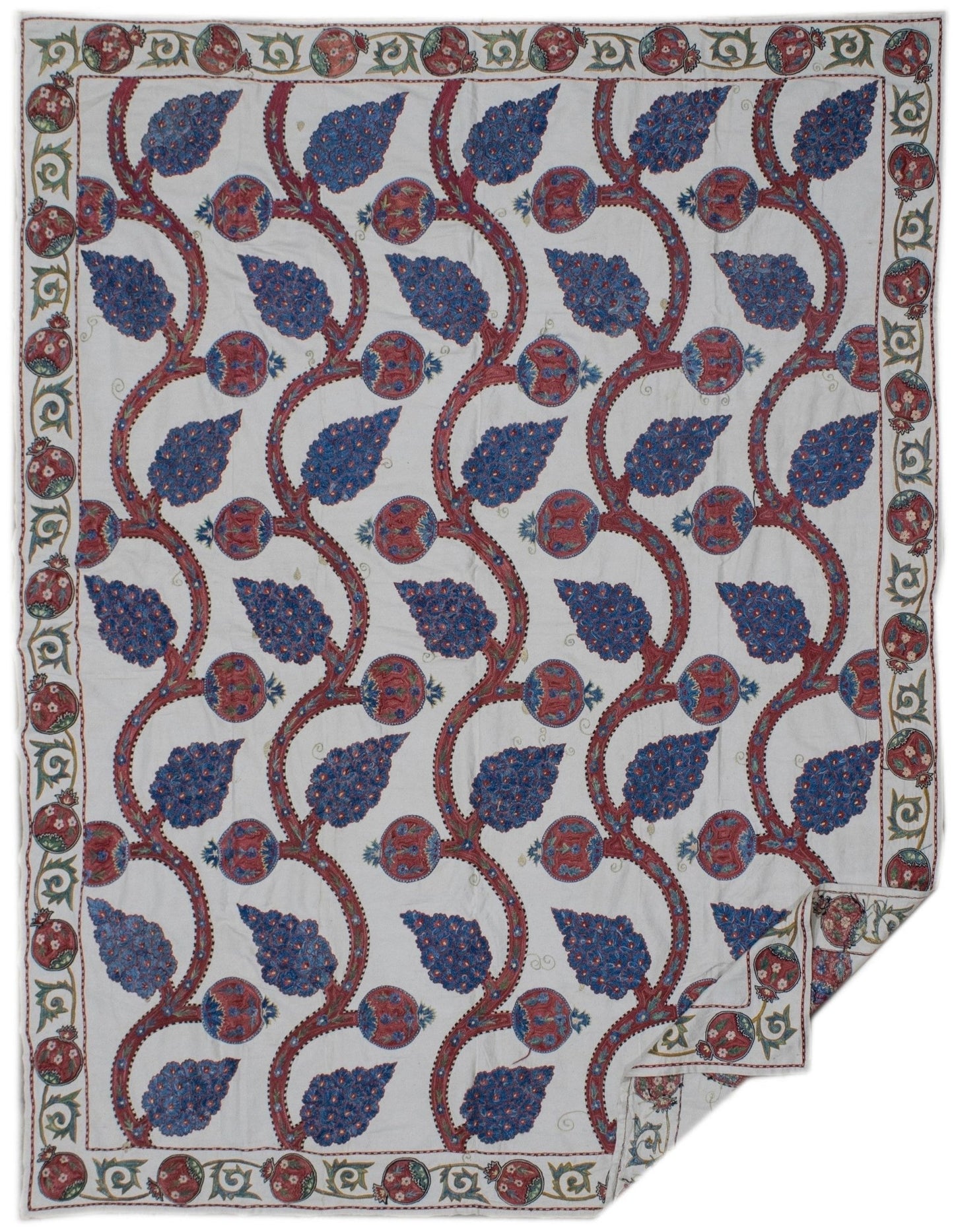 Handmade Uzbek suzani featuring blue and red floral embroidery on a white cotton base.