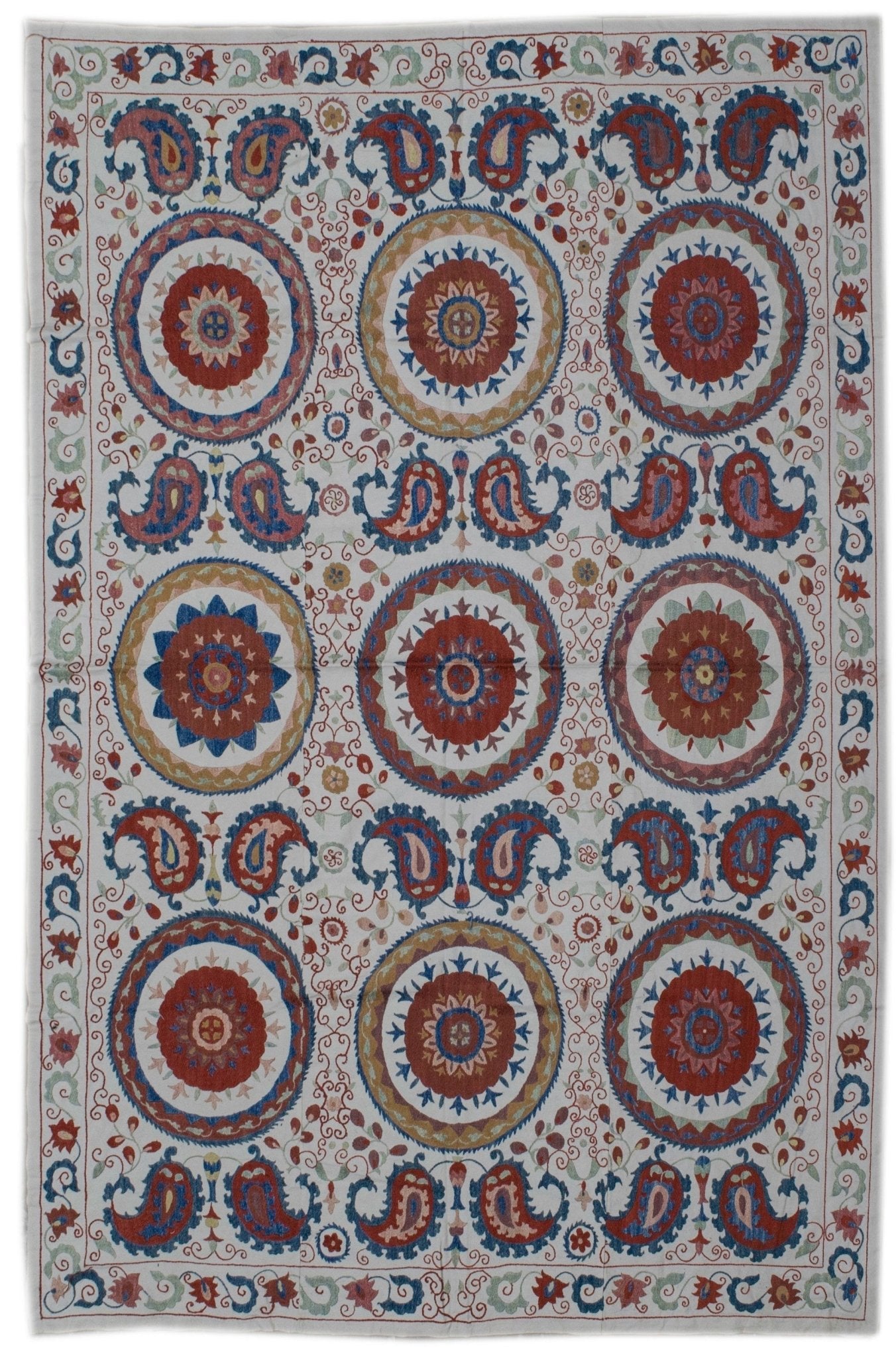Handmade Uzbek suzani featuring silk floral and paisley embroidery on a white cotton base.