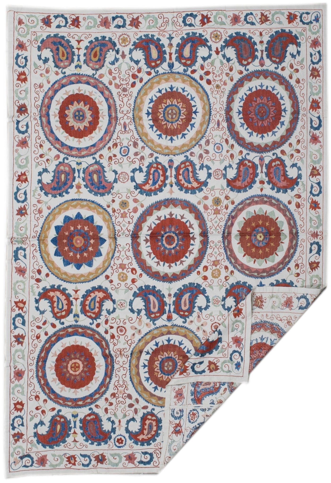 Handmade Uzbek suzani featuring silk floral and paisley embroidery on a white cotton base.