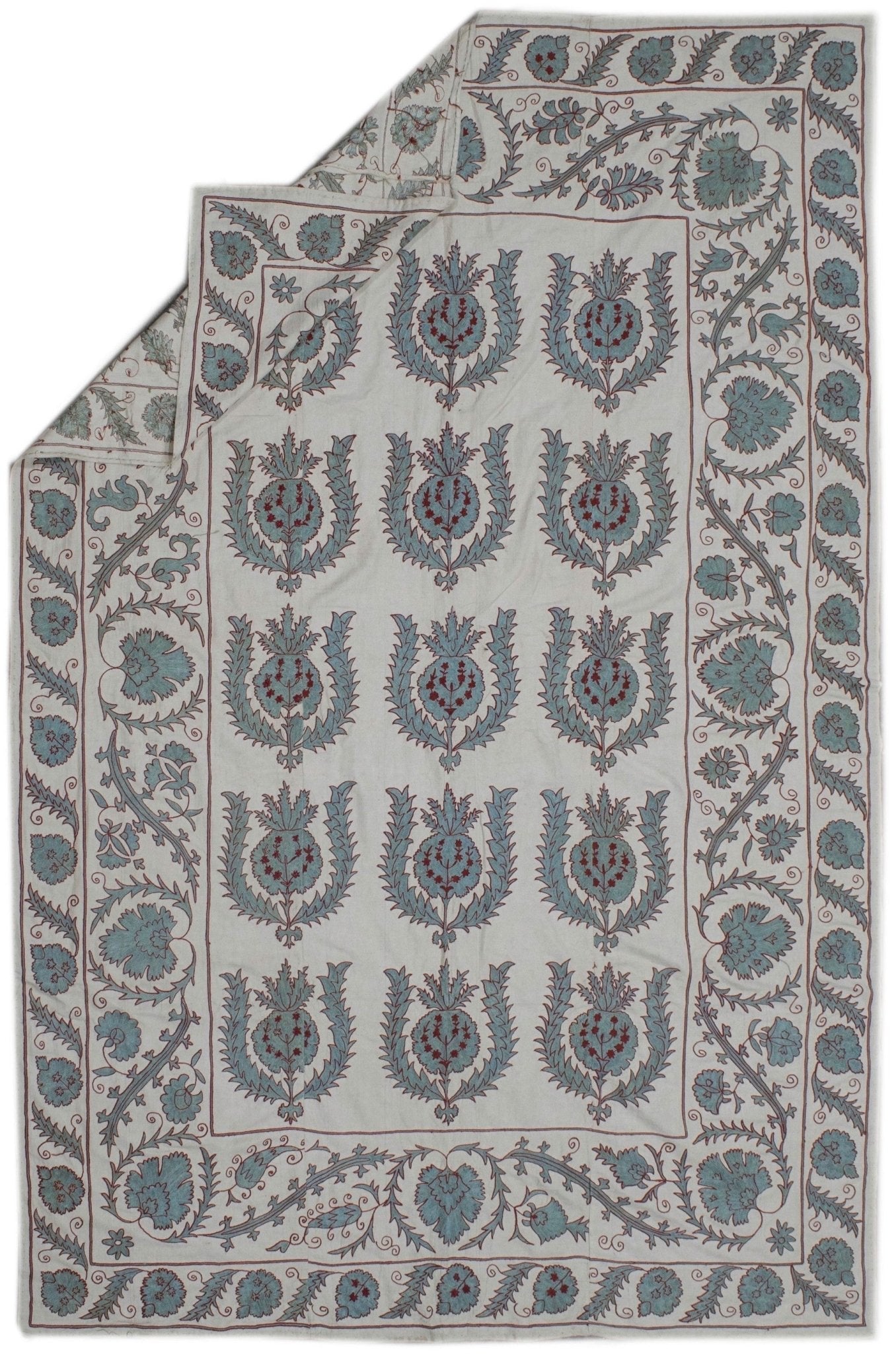 Handmade Uzbek suzani featuring blue and red floral embroidery on a white silk background.