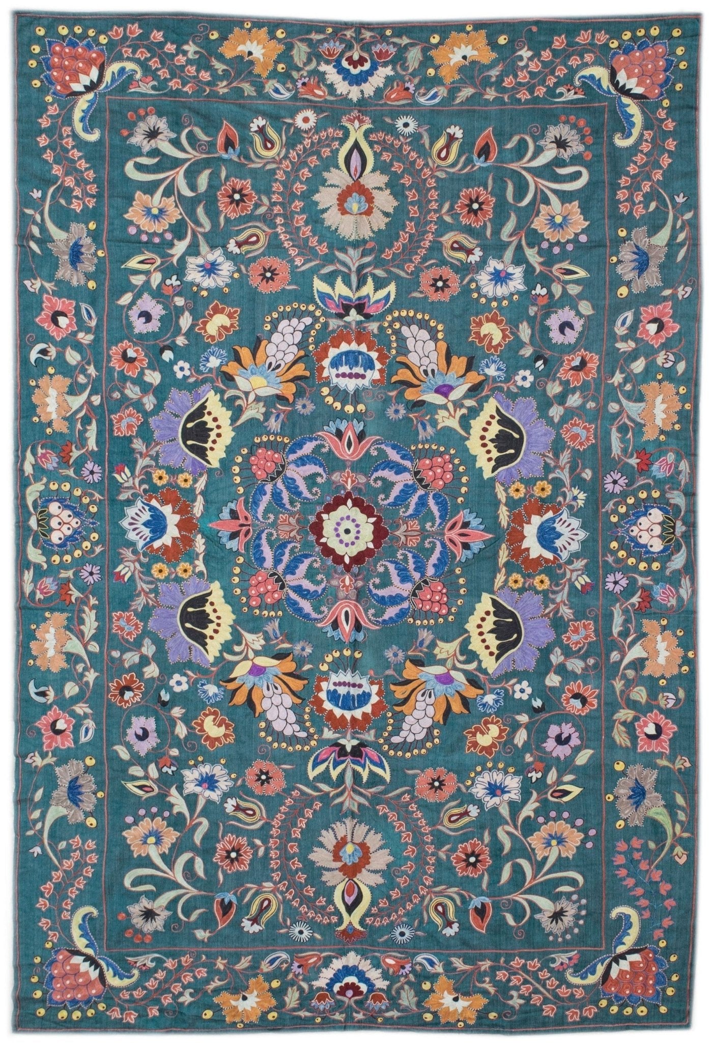 Handmade Uzbek suzani featuring intricate silk floral embroidery on a teal silk fabric base.