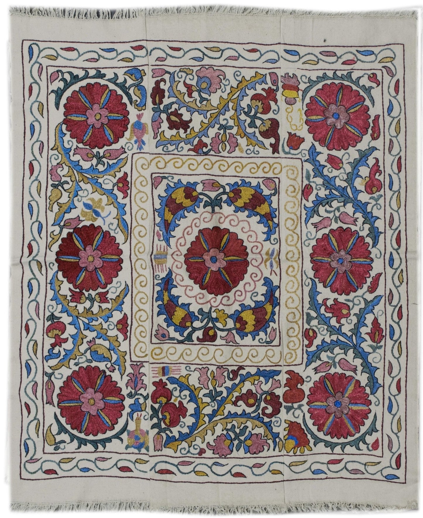 A square Uzbek suzani featuring vibrant silk floral embroidery on a white cotton base.