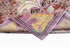 A handwoven Afghan rug featuring a floral botanical pattern in shades of pink, gold, and cream.