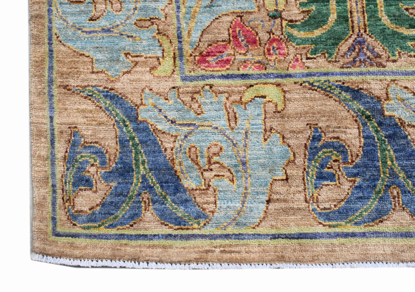 A handwoven Afghan rug featuring a transitional botanical pattern in blue, green, and tan tones.