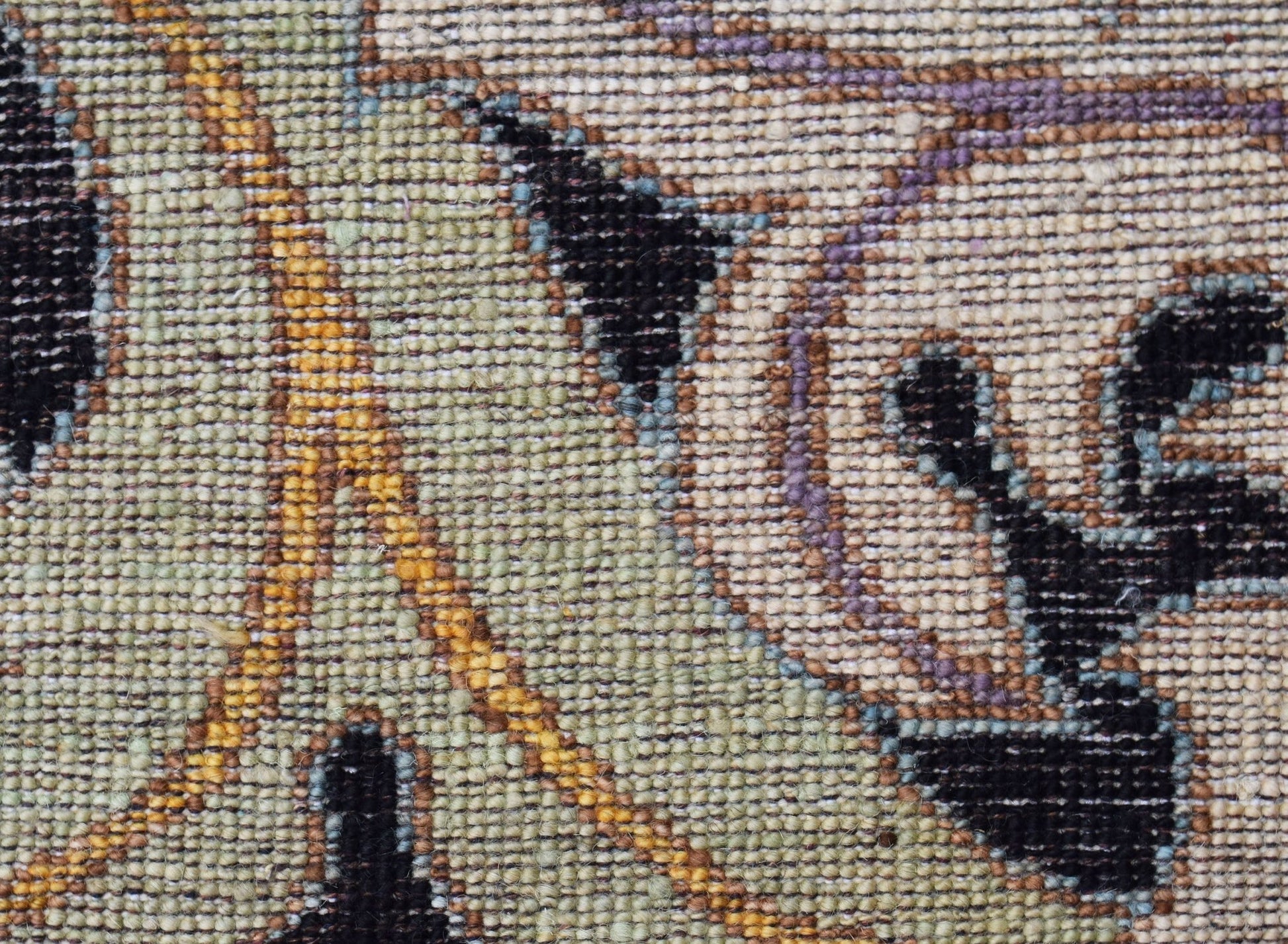 A close-up view of a handwoven Afghan rug featuring a floral pattern in muted tones.