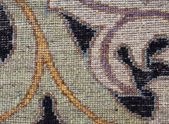 A close-up view of a handwoven Afghan rug featuring a floral pattern in muted tones.