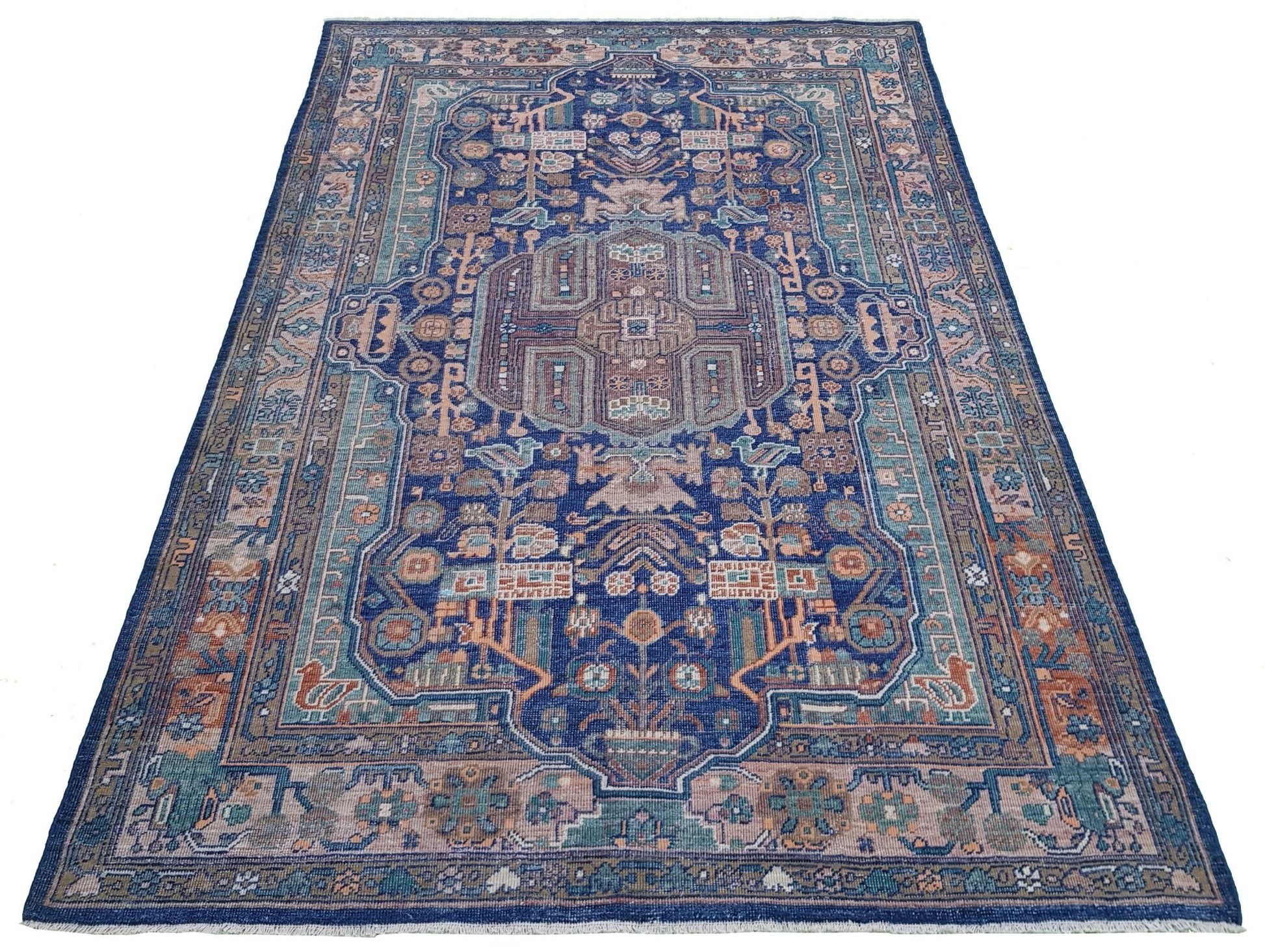 A rectangular Afghan rug featuring a traditional geometric pattern in blue, tan, and muted tones.