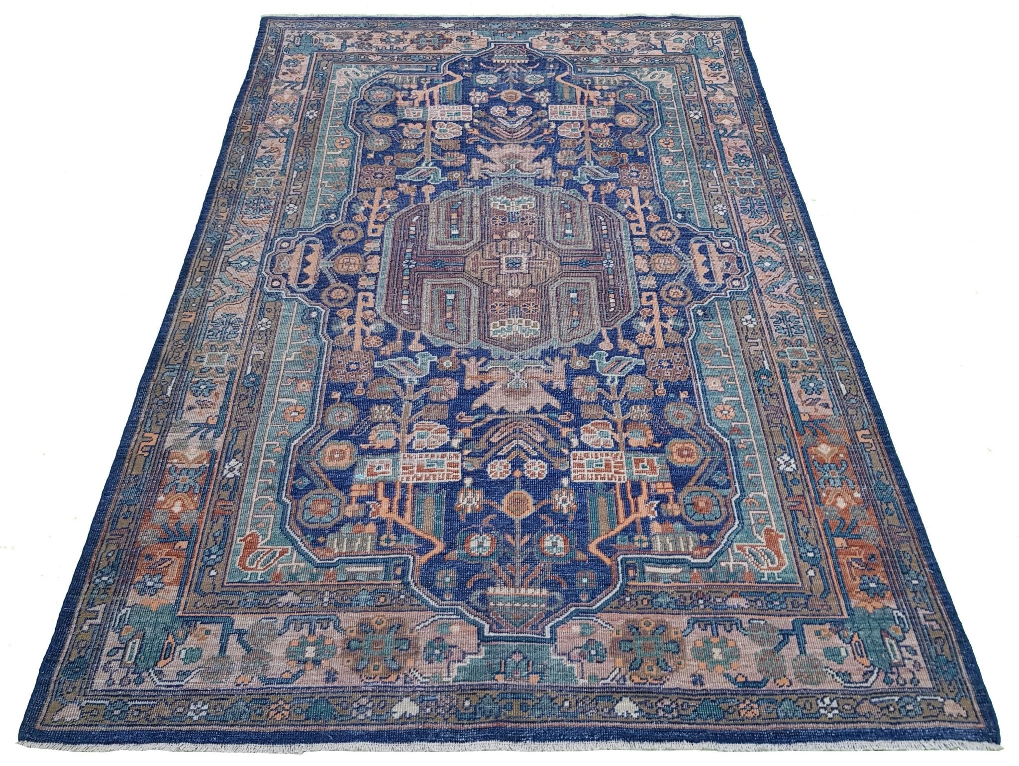 A rectangular Afghan rug featuring a traditional geometric pattern in blue, tan, and muted tones.