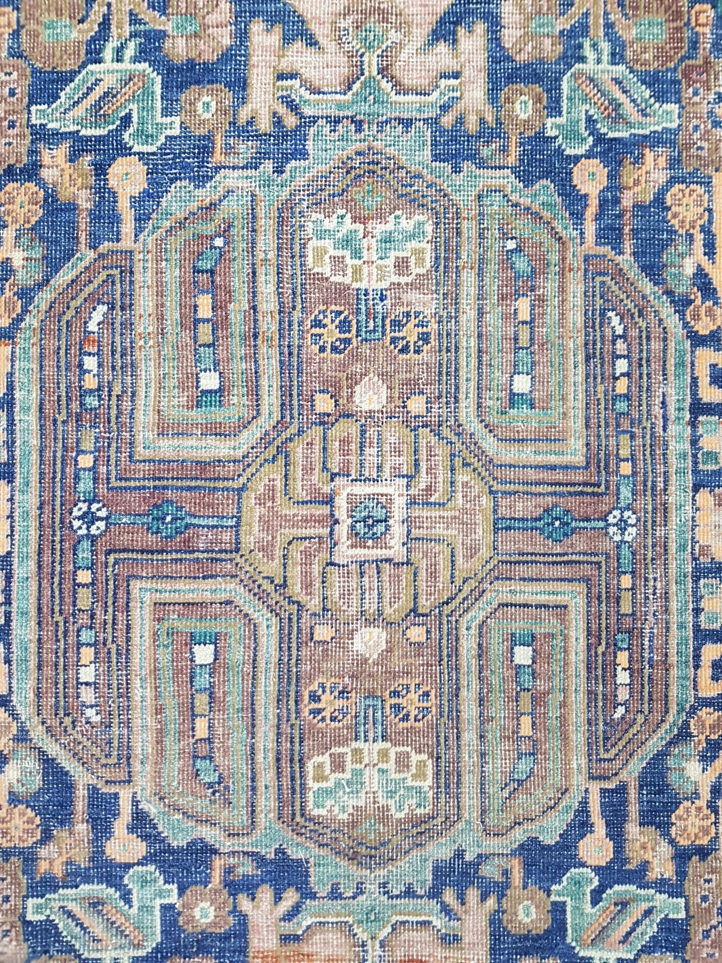 A handmade Afghan rug featuring a geometric pattern in shades of blue, brown, and cream.