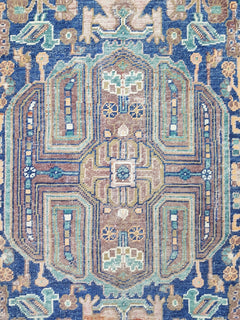 A handmade Afghan rug featuring a geometric pattern in shades of blue, brown, and cream.