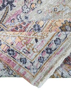 A folded transitional Oushak rug featuring a traditional pattern in muted, multi-colored tones.