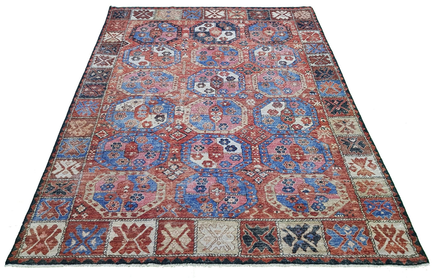A handmade Afghan rug featuring a traditional geometric pattern in shades of red and blue.
