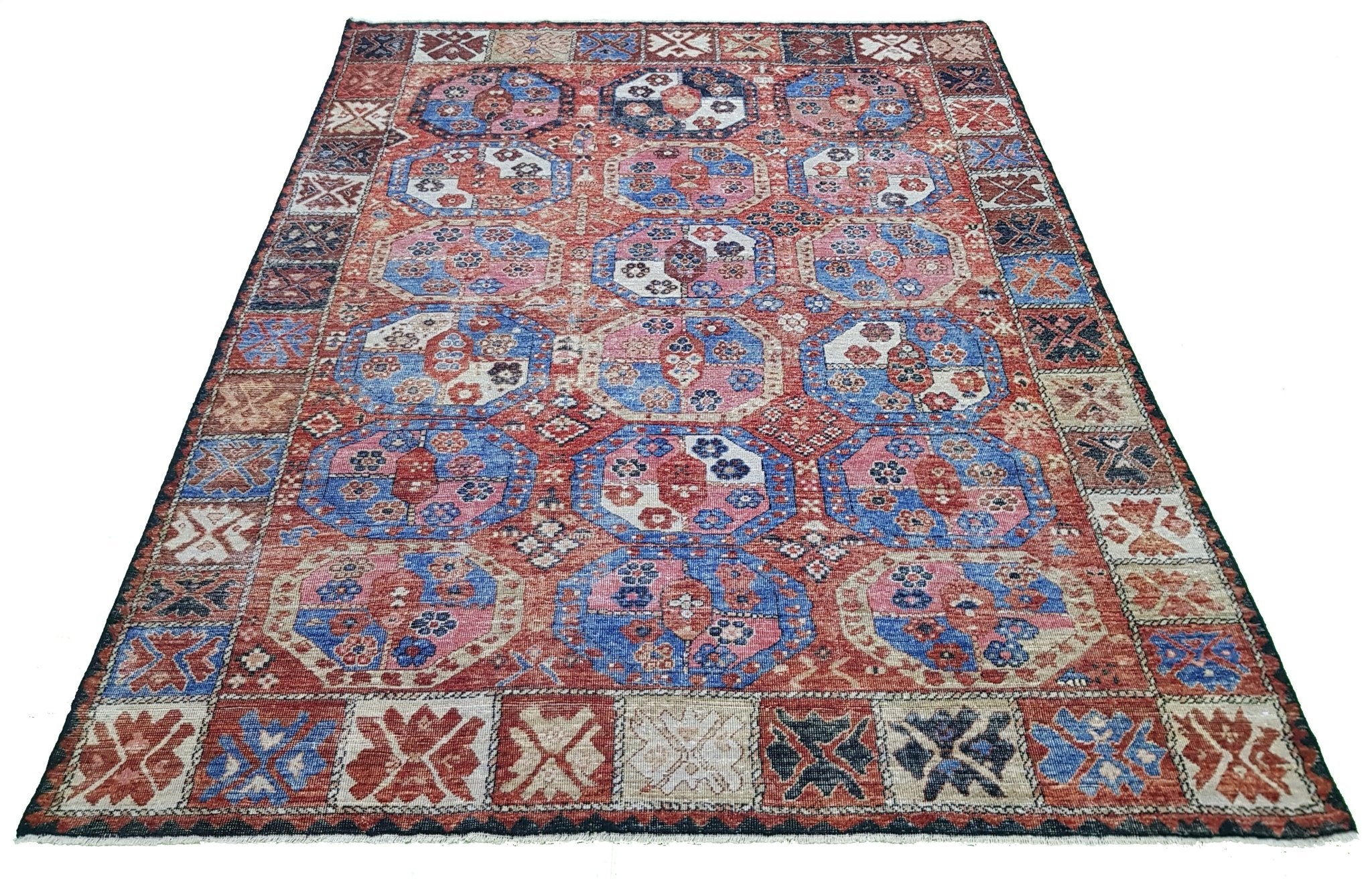 A handmade Afghan rug featuring a traditional geometric pattern in shades of red and blue.