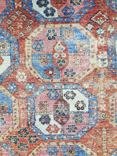 Handwoven Afghan rug featuring a geometric Elephant Foot pattern in red, blue, and cream tones.