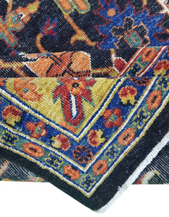 A folded transitional Afghan rug featuring a black background with intricate floral patterns.