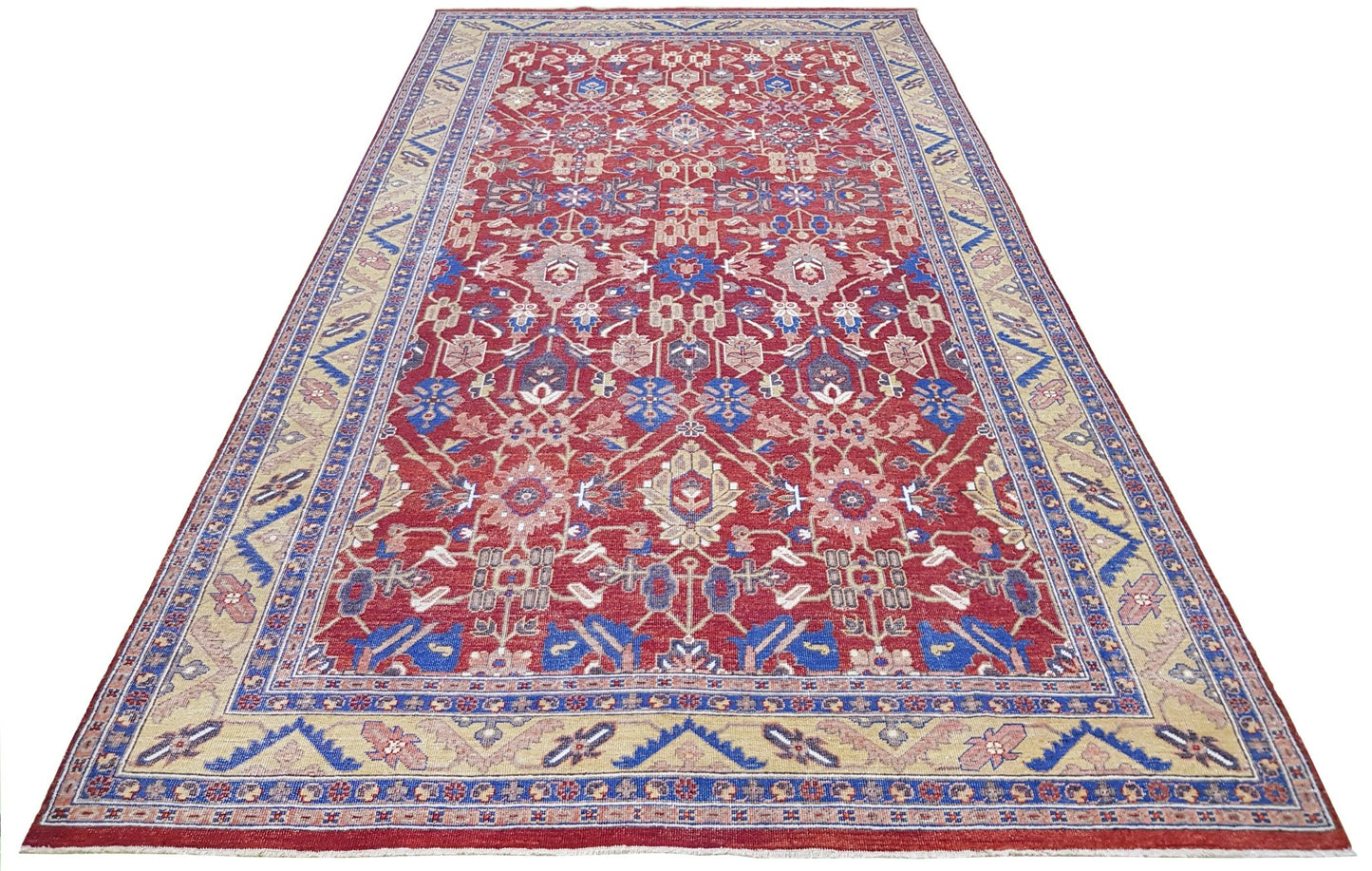 A rectangular transitional Afghan rug featuring a red field with a floral medallion and blue borders.