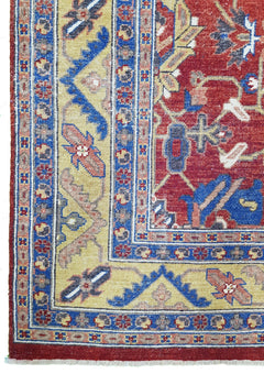 A hand-knotted Afghan rug featuring a red field with intricate floral patterns and blue borders.