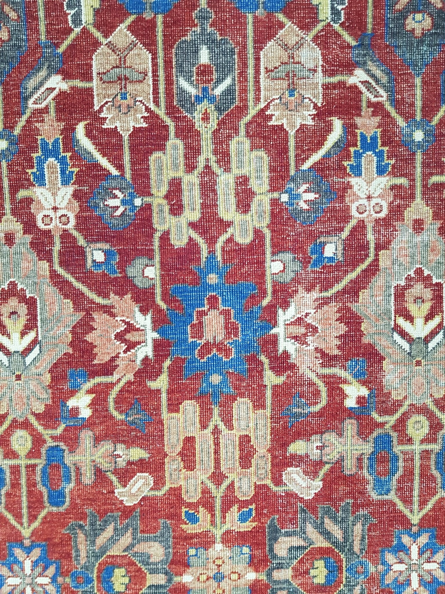 A vintage Afghan rug featuring an intricate floral medallion pattern in red, blue, and cream tones.