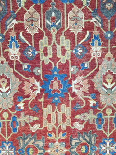 A vintage Afghan rug featuring an intricate floral medallion pattern in red, blue, and cream tones.