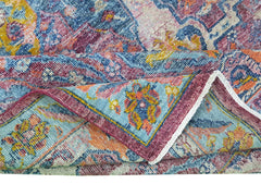 A folded transitional Afghan rug featuring a colorful floral pattern in blue, pink, and orange.