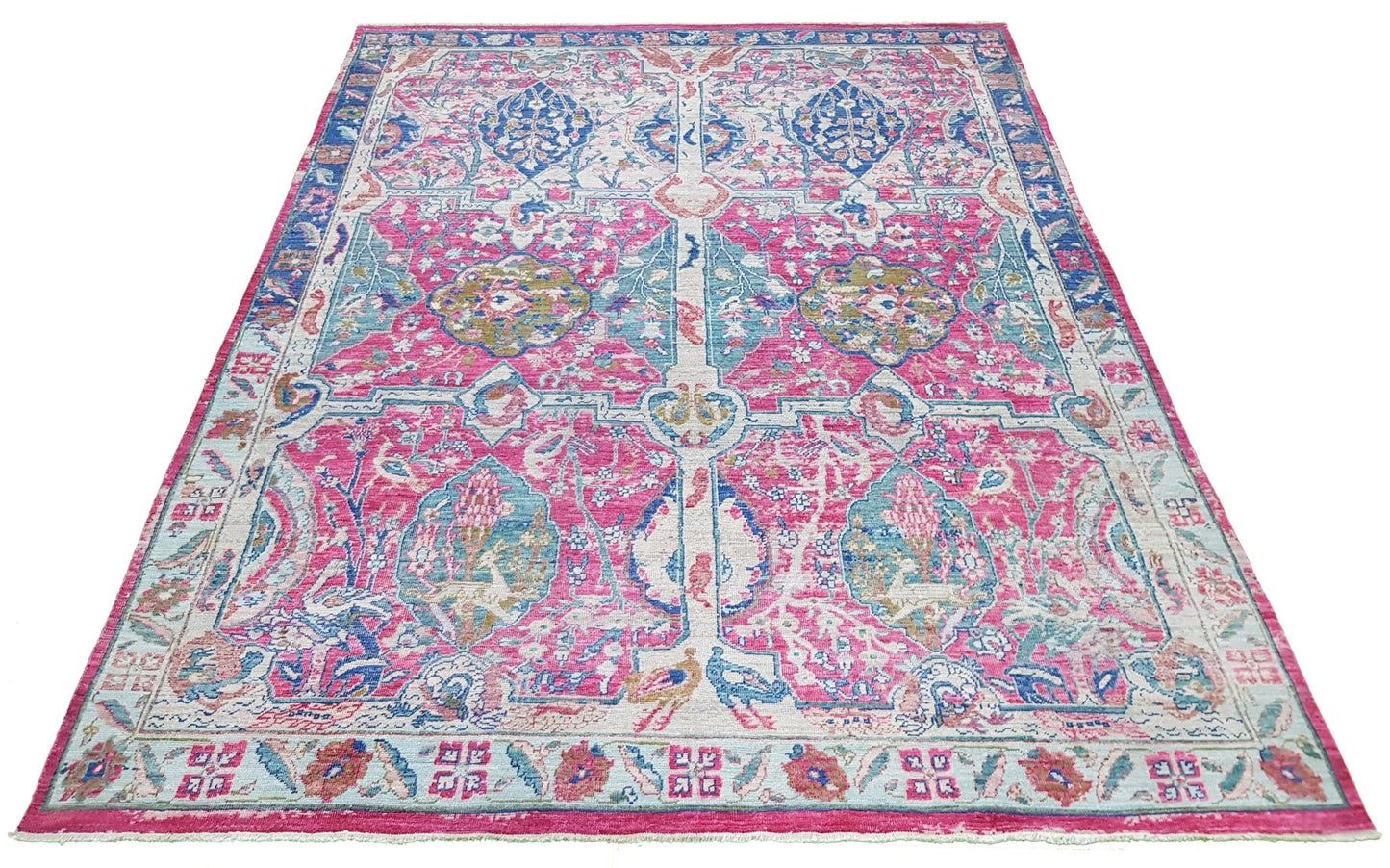 A handmade Afghan rug featuring a vibrant pink and blue Tree of Life pattern on a low pile.