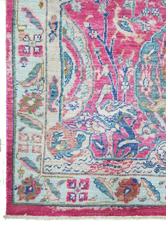 A handmade Afghan rug featuring a vibrant pink and blue Tree of Life pattern on a light background.