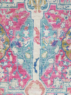 A transitional Afghan rug featuring a Tree of Life pattern in vibrant pink and teal tones.