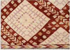 A hand-knotted wool rug featuring a geometric pattern of cream diamonds on a rust red background.