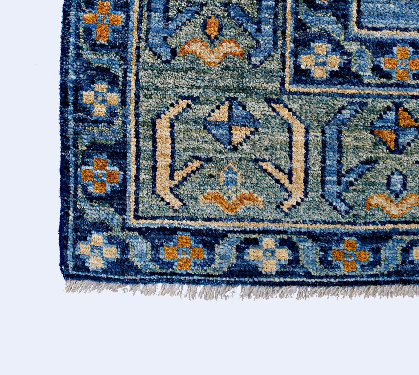 A handmade wool rug from Afghanistan featuring a blue and teal geometric pattern with fringe.