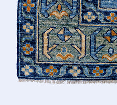 A handmade wool rug from Afghanistan featuring a blue and teal geometric pattern with fringe.