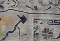 A close-up view of a hand-knotted wool rug featuring geometric patterns in muted earth tones.