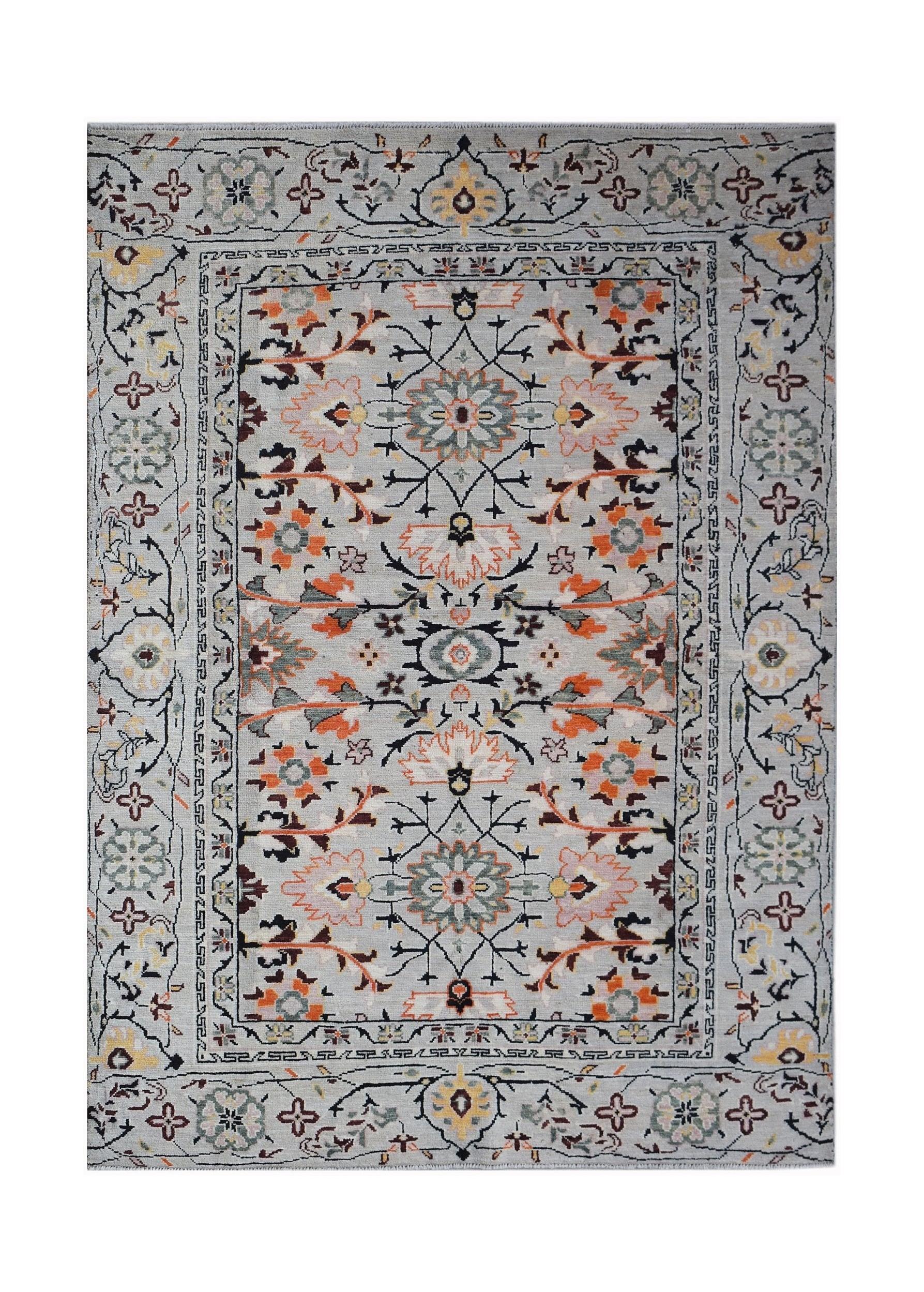 A hand-knotted wool rug featuring a light grey background with intricate floral and vine patterns.