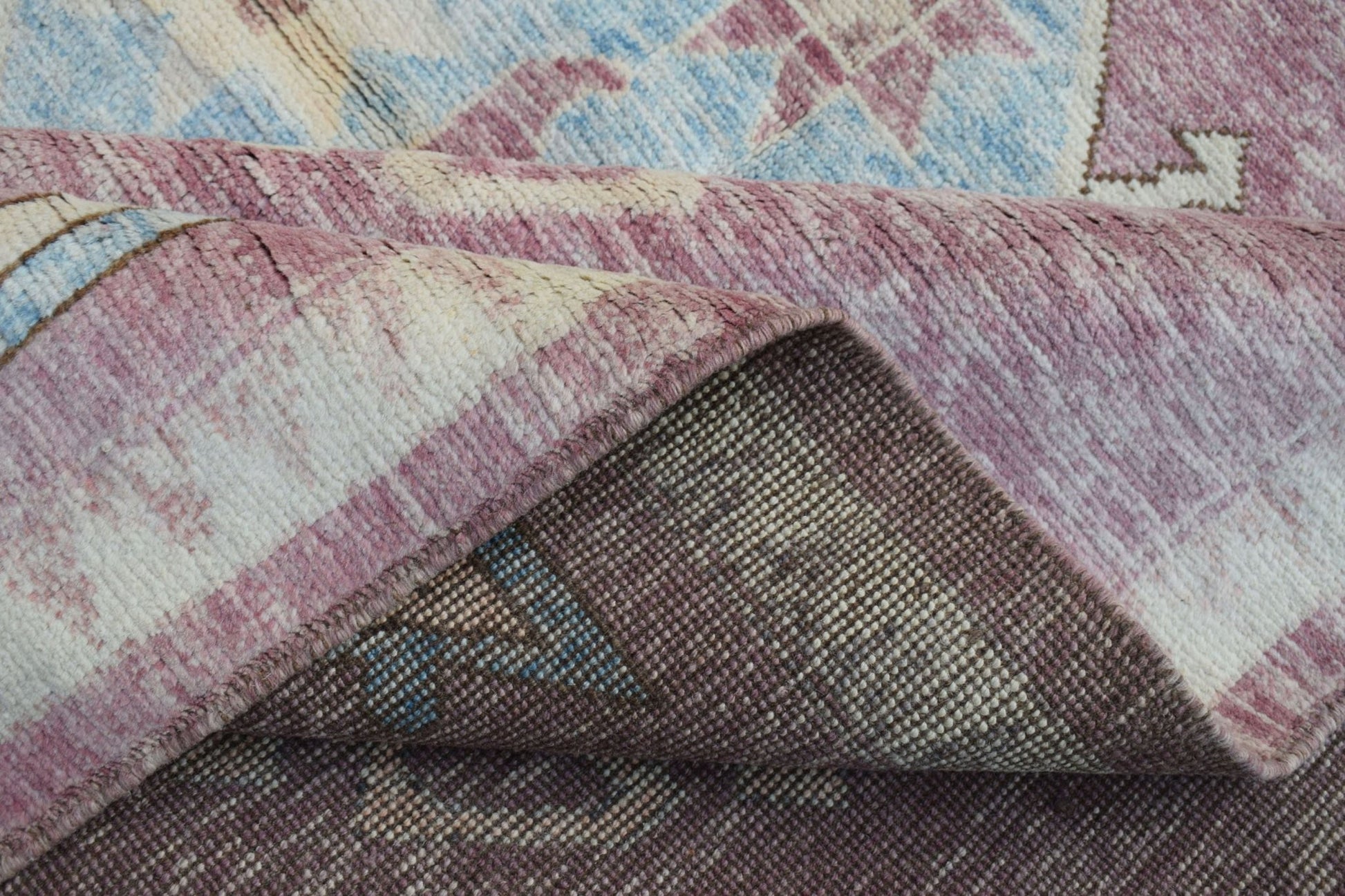 A corner of a handmade wool rug from Afghanistan showing its plush pile and woven backing.
