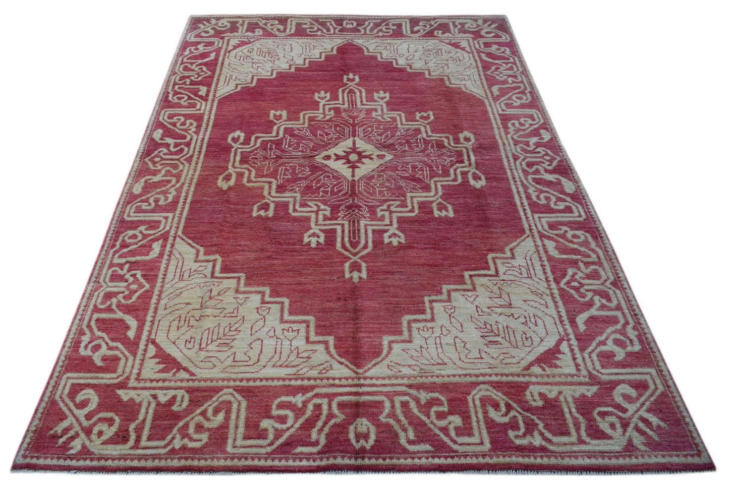 A handmade wool rug from Afghanistan featuring a geometric medallion pattern in red and cream.