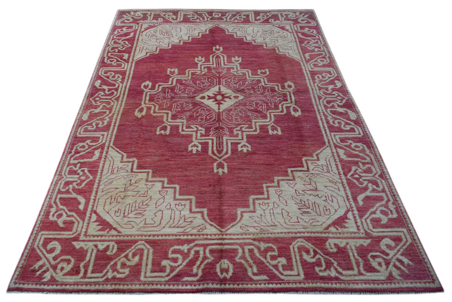 A handmade wool rug from Afghanistan featuring a geometric medallion pattern in red and cream.