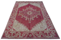 A handmade wool rug from Afghanistan featuring a geometric medallion pattern in red and cream.
