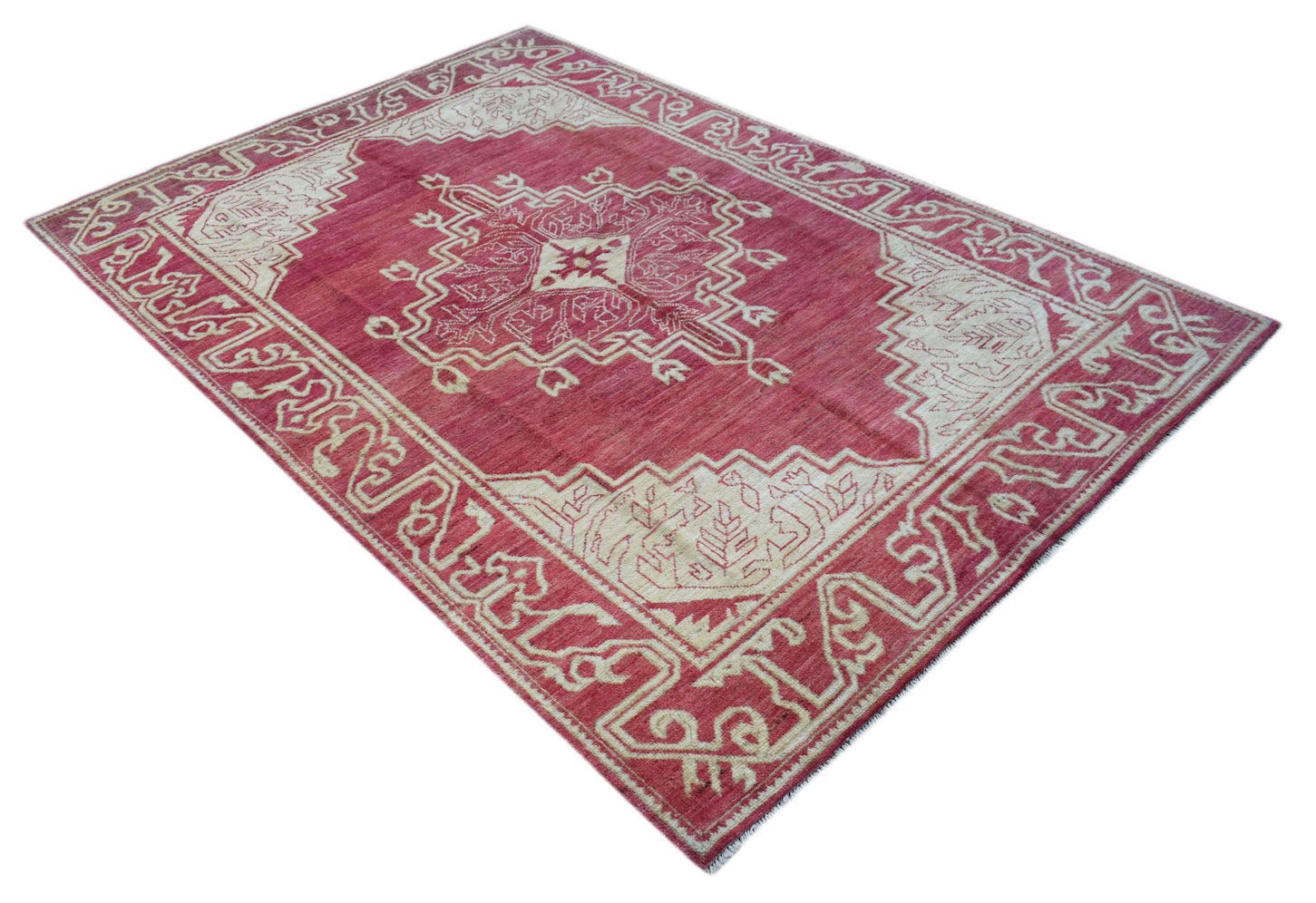 A handmade Afghan wool rug featuring a geometric medallion pattern in red and cream tones.