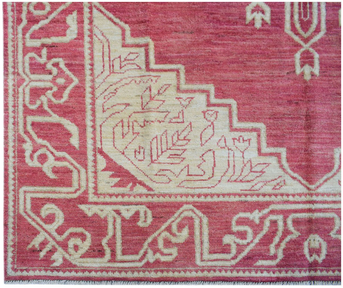 A handmade Afghan wool rug featuring a geometric cream pattern on a vibrant pink background.