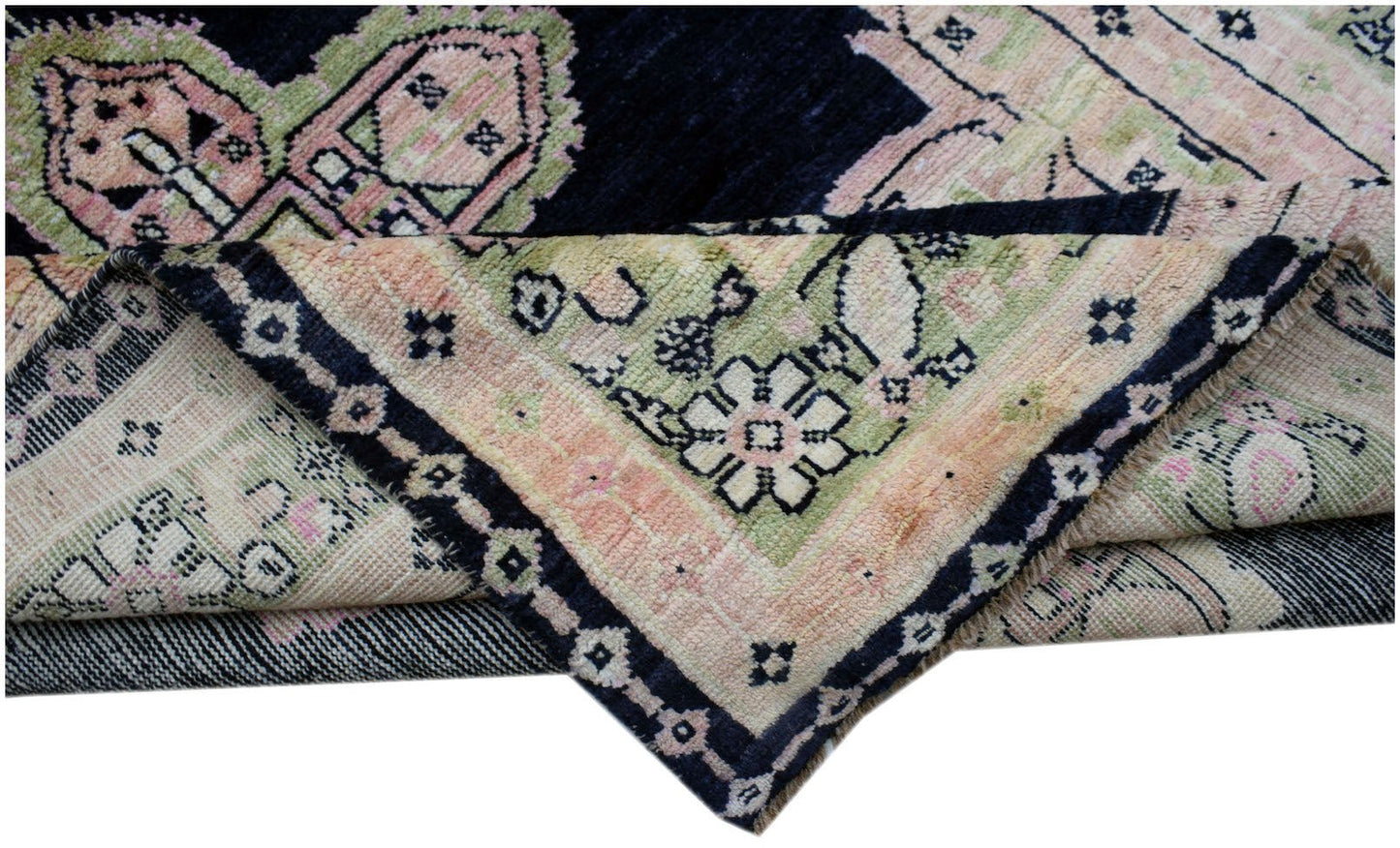 A handmade wool rug from Afghanistan featuring a dark blue field with pink and green floral motifs.