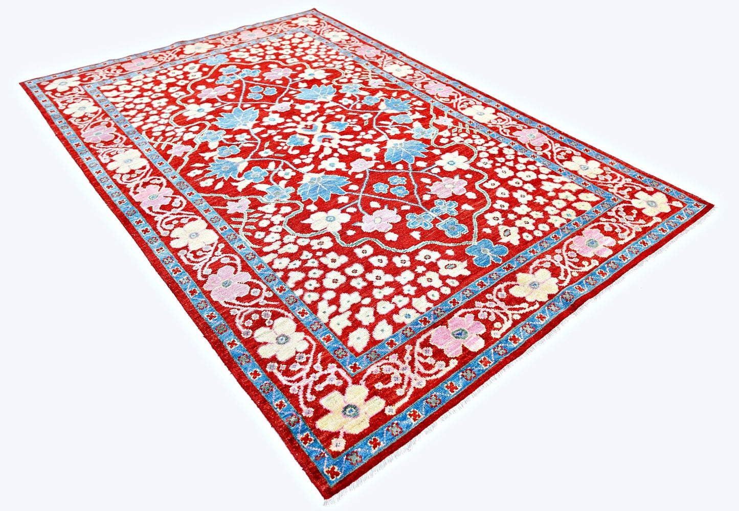 A handmade red wool rug from Afghanistan featuring a floral pattern and a blue border.