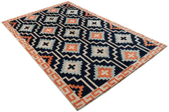 A hand-knotted wool rug featuring a dark blue background with geometric orange and grey patterns.